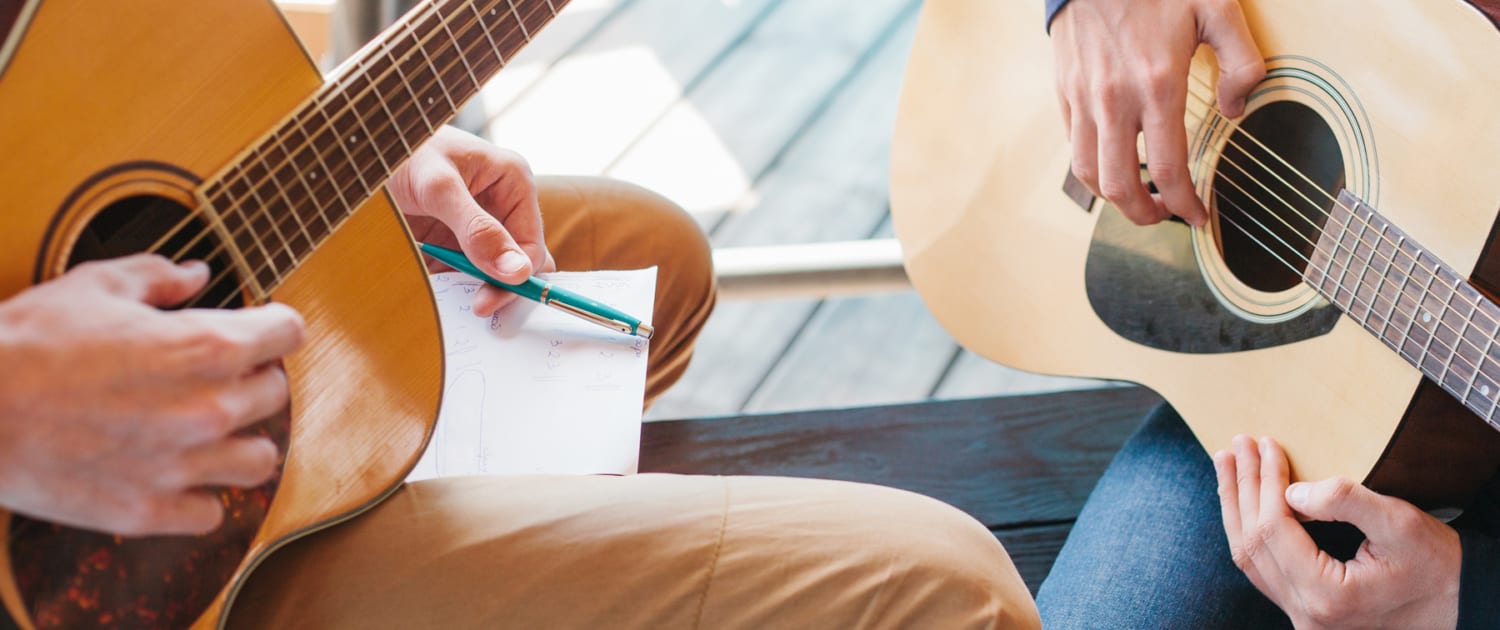 Two musicians play their guitars together.